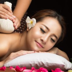 Asian woman getting thai herbal compress massage in spa.She is very relaxed